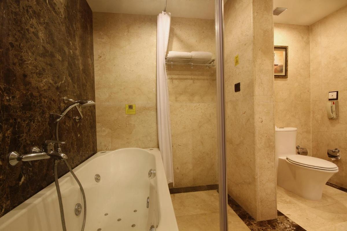 a bathroom with a shower and a tub and a toilet at Fortune Select JP Cosmos, Bengaluru - Member ITC Hotels' Group in Bengaluru