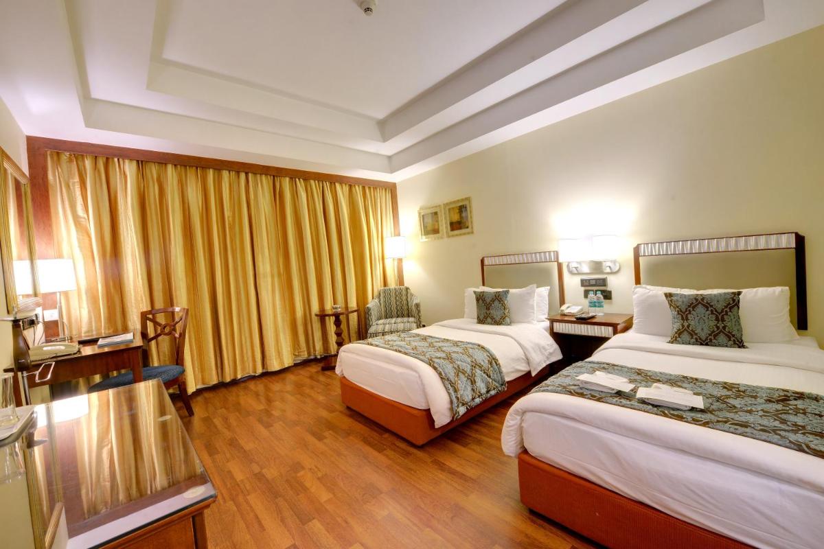 a hotel room with two beds and a desk at Fortune Select JP Cosmos, Bengaluru - Member ITC Hotels' Group in Bengaluru