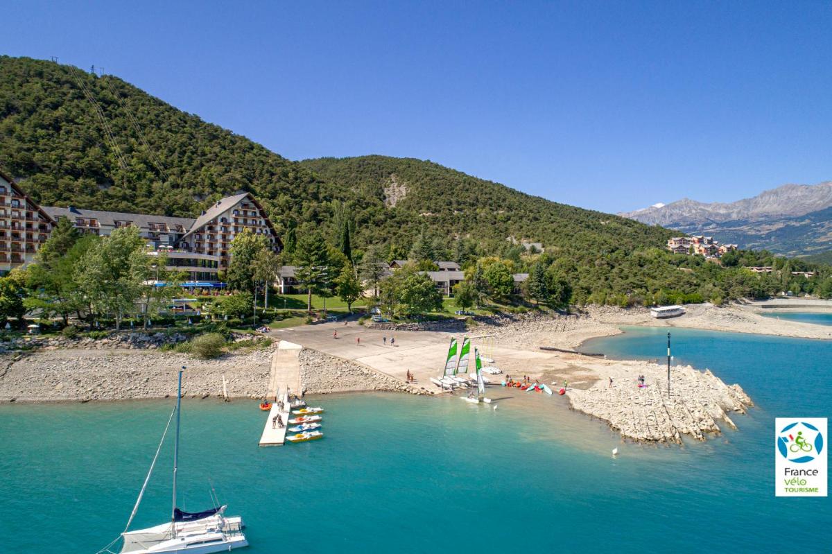 une plage avec des bateaux dans l'eau et un groupe de personnes dans l'établissement Village Club Les Hyvans, à Chorges