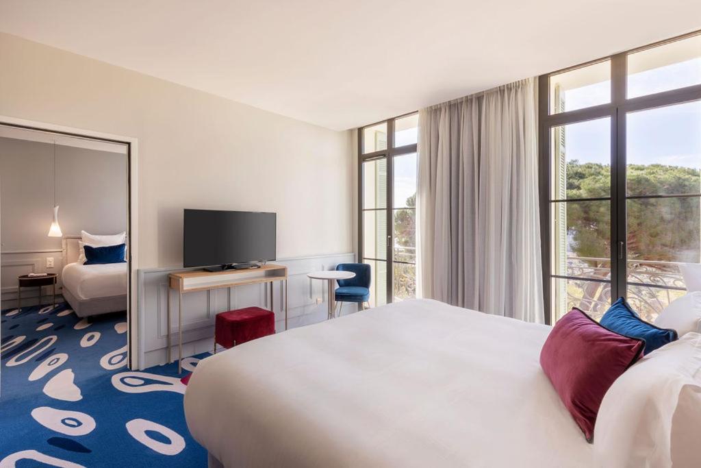 une chambre d'hôtel avec un lit, un bureau et une télévision dans l'établissement Eden Rose Grand Hotel BW Premier Collection, à Bormes-les-Mimosas 98 autres photos