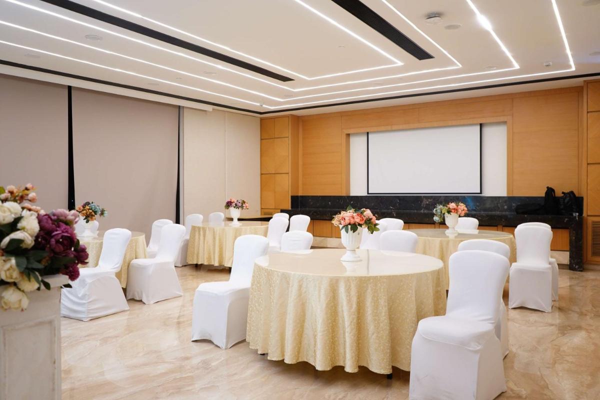 a room with tables and white chairs and a projection screen at Hilton Garden Inn Pune Hinjawadi in Pune