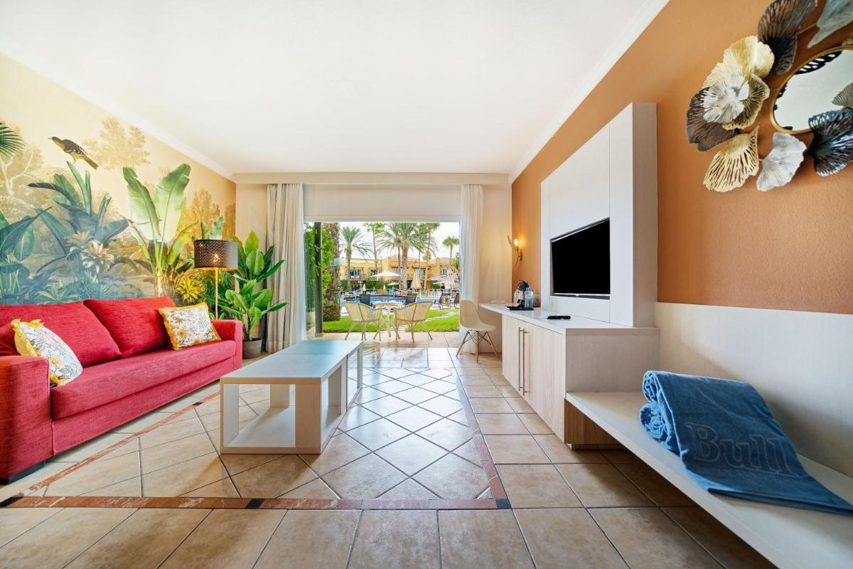 Una sala de estar con un sofá rojo y un televisor. en Bull Vital Suites & Spa Boutique Hotel - Only Adults, en Playa del Inglés