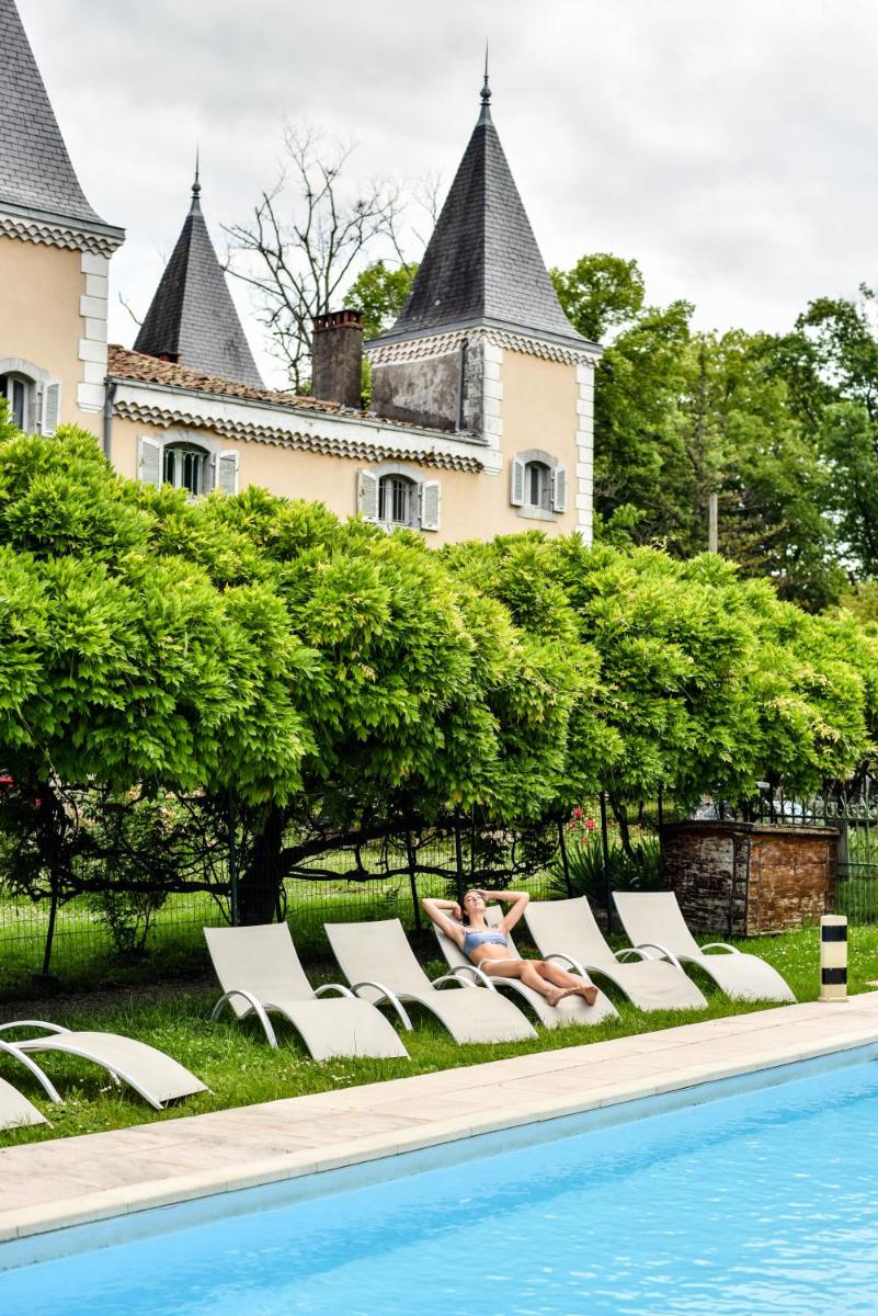 une femme assise sur des chaises longues à côté d'une piscine dans l'établissement Hotel Logis - Chateau de Beauregard, à Saint-Girons
