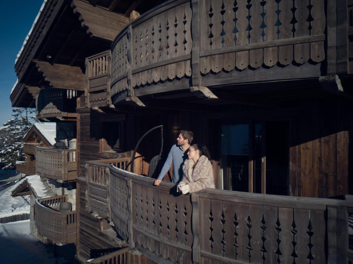 un homme et une femme debout sur un balcon d'une maison dans l'établissement Six Senses Residences & Spa Courchevel, à Courchevel