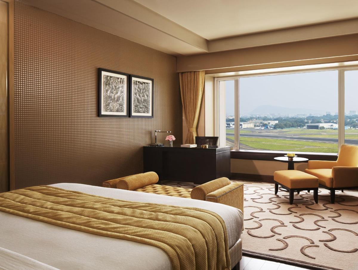 a hotel room with a bed and a large window at Taj Santacruz in Mumbai