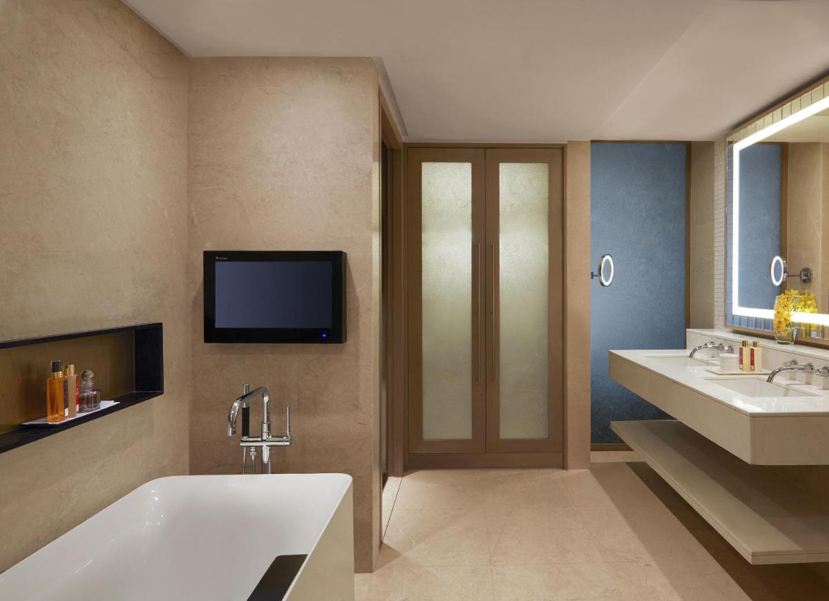 a bathroom with a tub and two sinks and a tv at Taj Santacruz in Mumbai