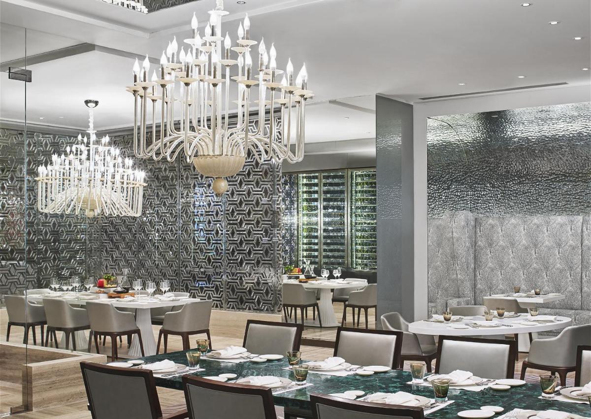 a dining room with tables and chairs and a chandelier at Taj Santacruz in Mumbai