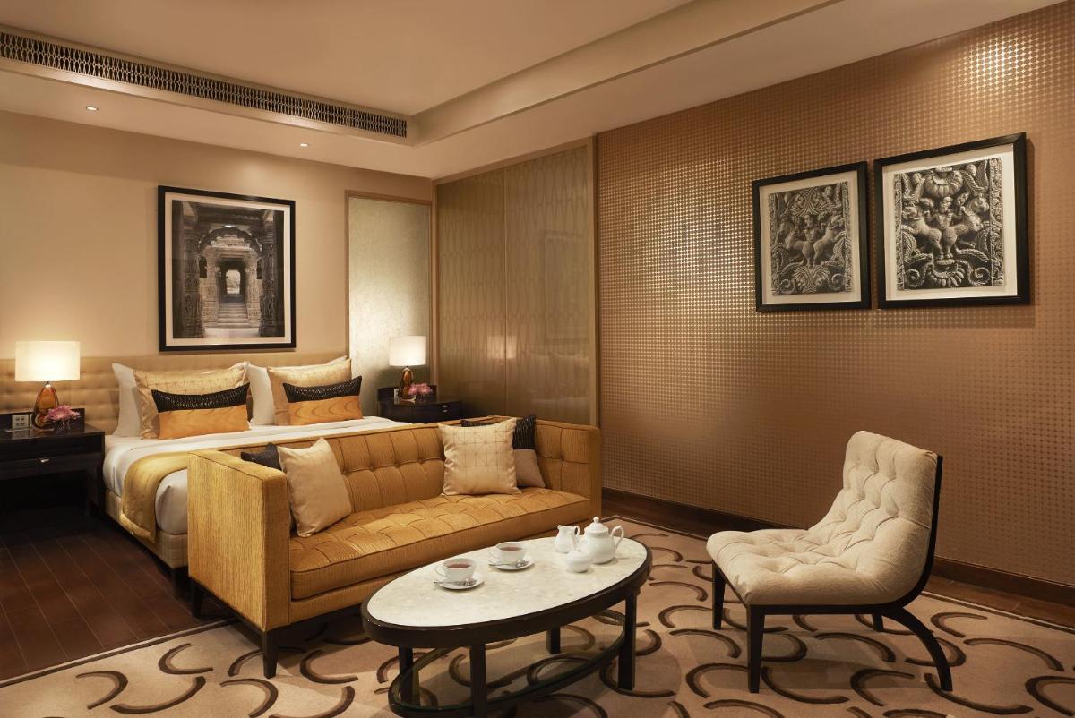 a hotel room with a bed and a couch and a table at Taj Santacruz in Mumbai