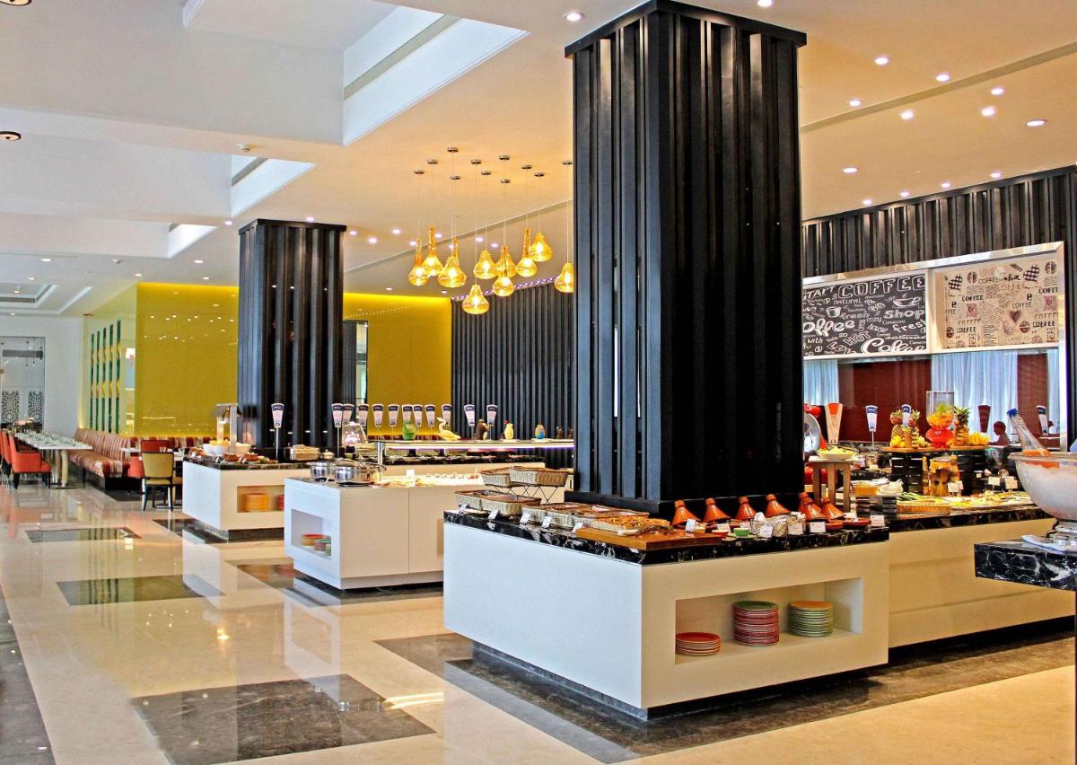 a restaurant with a buffet line in a mall at Radisson Blu Bengaluru Outer Ring Road in Bengaluru
