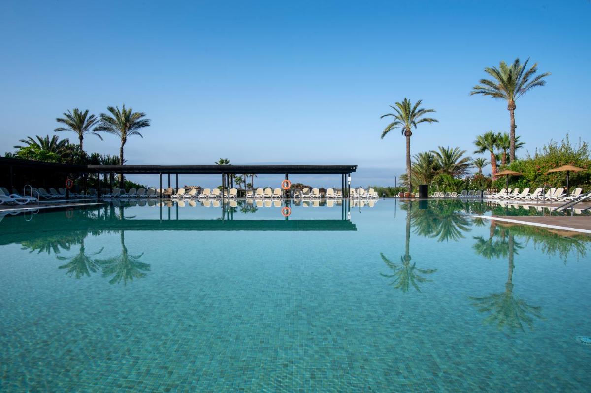 una gran piscina con palmeras y sillas en Impressive Playa Granada Golf, en Motril