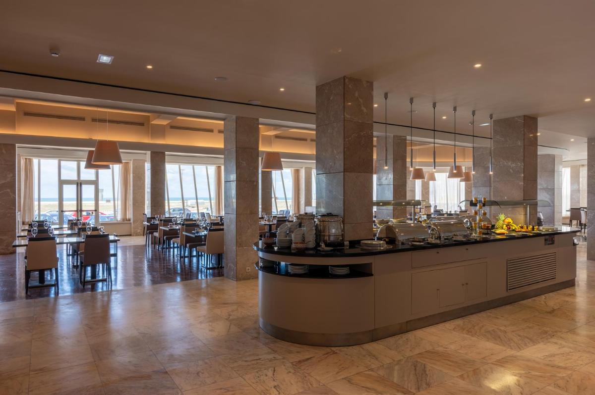 um restaurante com um bar com mesas e cadeiras em Vila Gale Collection Figueira da Foz na Figueira da Foz mais 45 fotografias