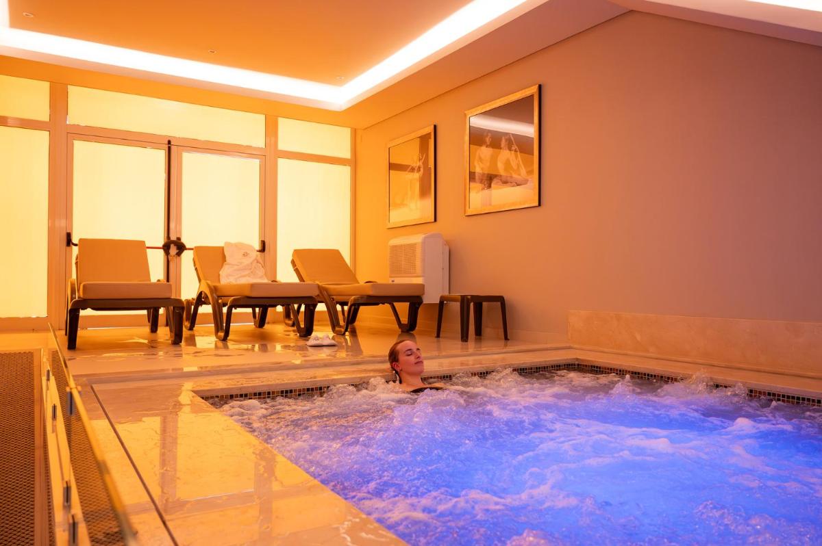 uma mulher está em uma banheira de hidromassagem em um quarto em Vila Gale Collection Figueira da Foz na Figueira da Foz