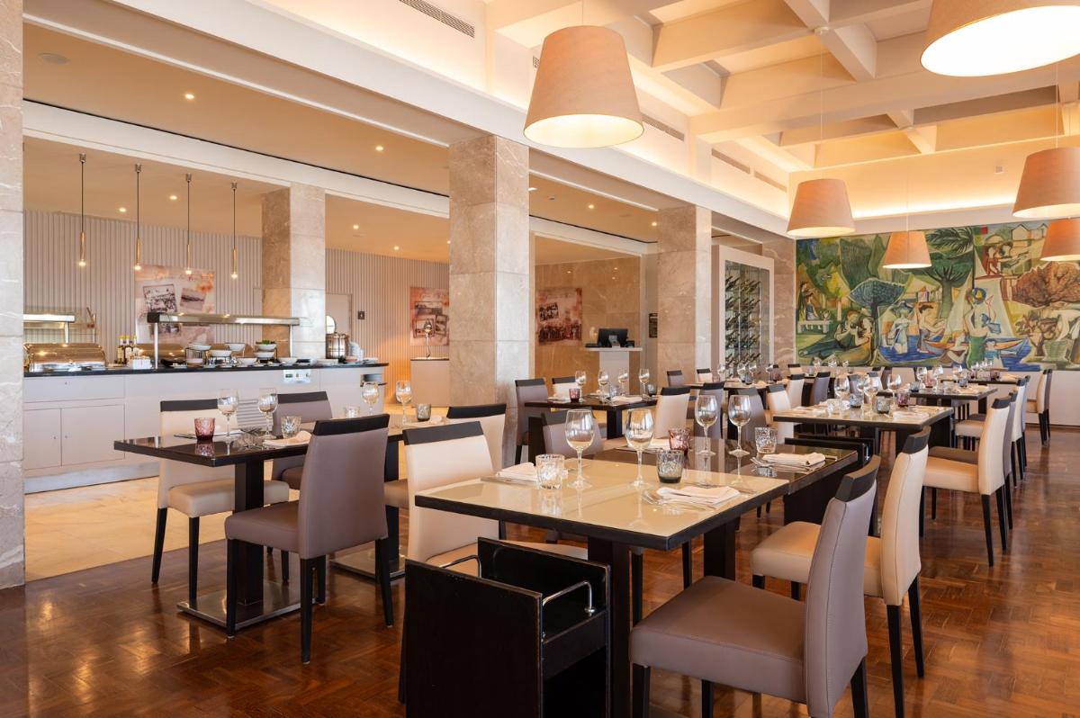 um restaurante com mesas e cadeiras e uma cozinha em Vila Gale Collection Figueira da Foz na Figueira da Foz