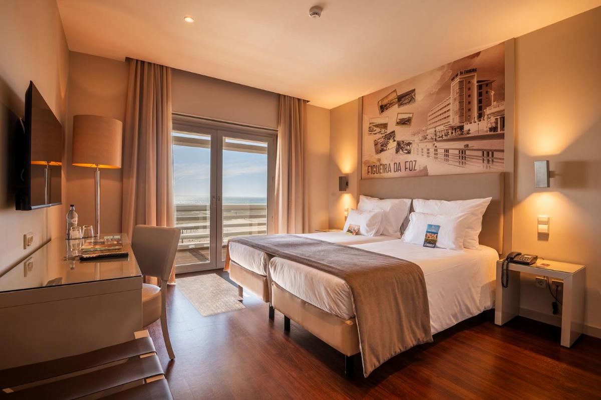 um quarto de hotel com uma cama e uma janela grande em Vila Gale Collection Figueira da Foz na Figueira da Foz