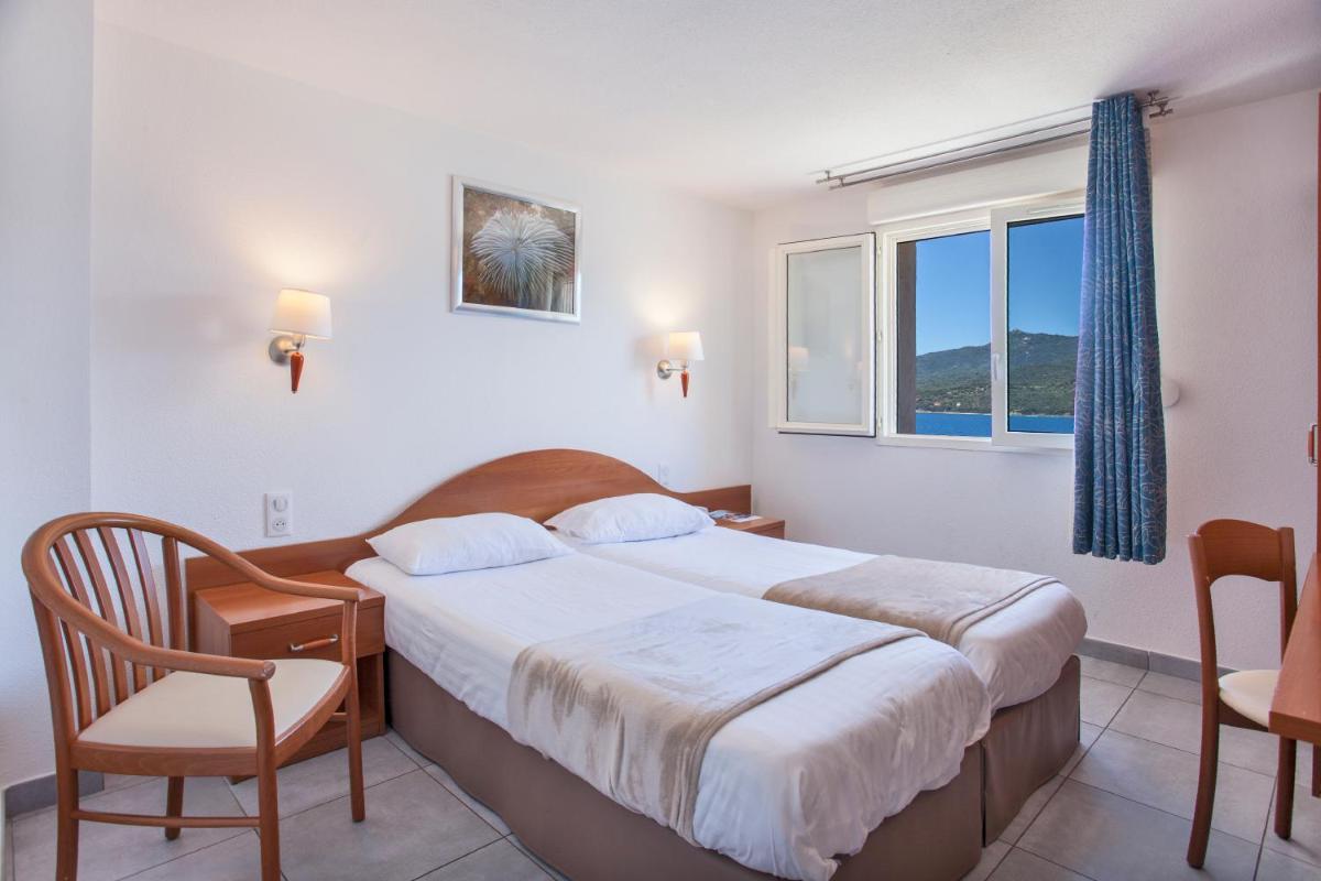 une chambre avec un lit, une chaise et une fenêtre dans l'établissement Le Neptune & Spa, à Propriano 62 autres photos