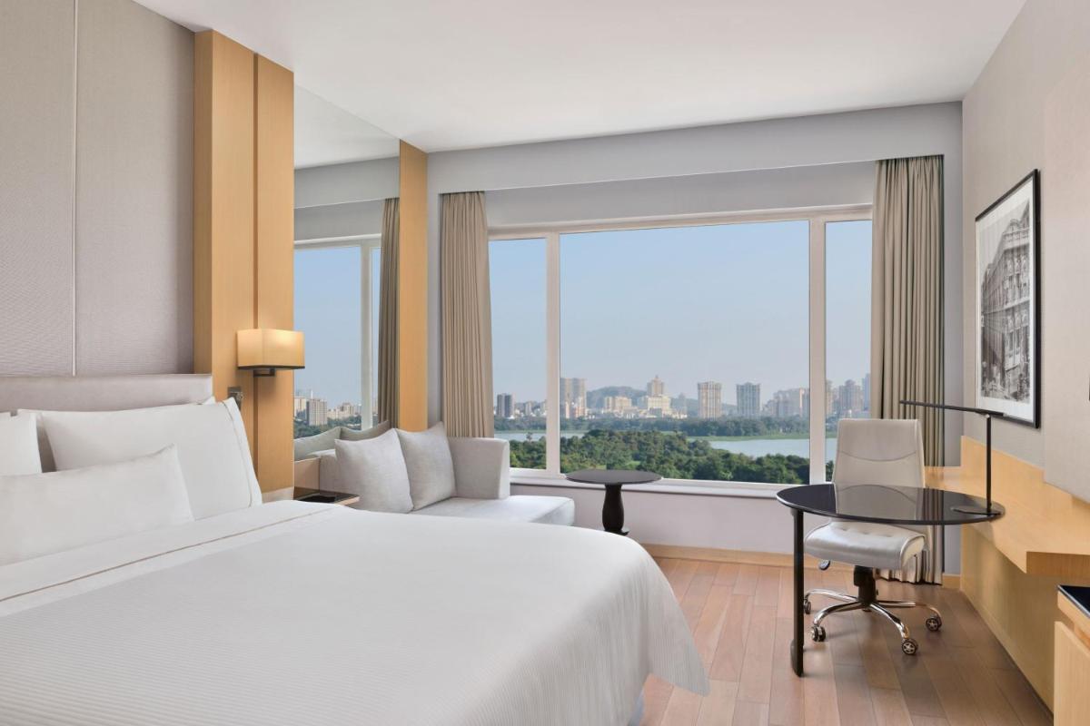 a hotel room with a bed and a large window at The Westin Mumbai Powai Lake in Mumbai
