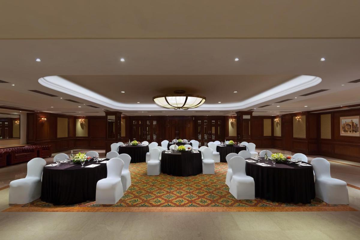 a banquet hall with tables and white chairs in a room at Sheraton New Delhi Hotel in New Delhi a banquet hall with tables and white chairs in a room at Sheraton New Delhi Hotel in New Delhi