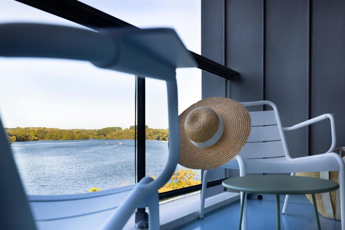 un chapeau assis sur une chaise devant une fenêtre dans l'établissement Best Western Plus Hotel les Rives du Ter, à Larmor-Plage
