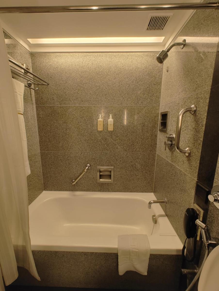 a bathroom with a bath tub and a toilet at Hotel Marine Plaza in Mumbai