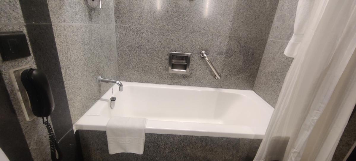 a white bath tub in a bathroom with a phone at Hotel Marine Plaza in Mumbai