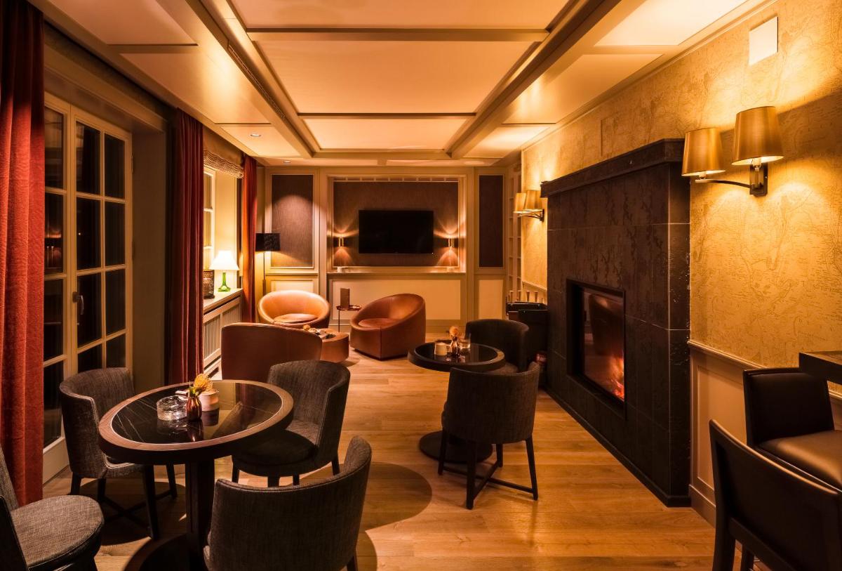 eine Hotellobby mit Tischen, Stühlen und einem Kamin in der Unterkunft Severin's Resort & Spa in Keitum