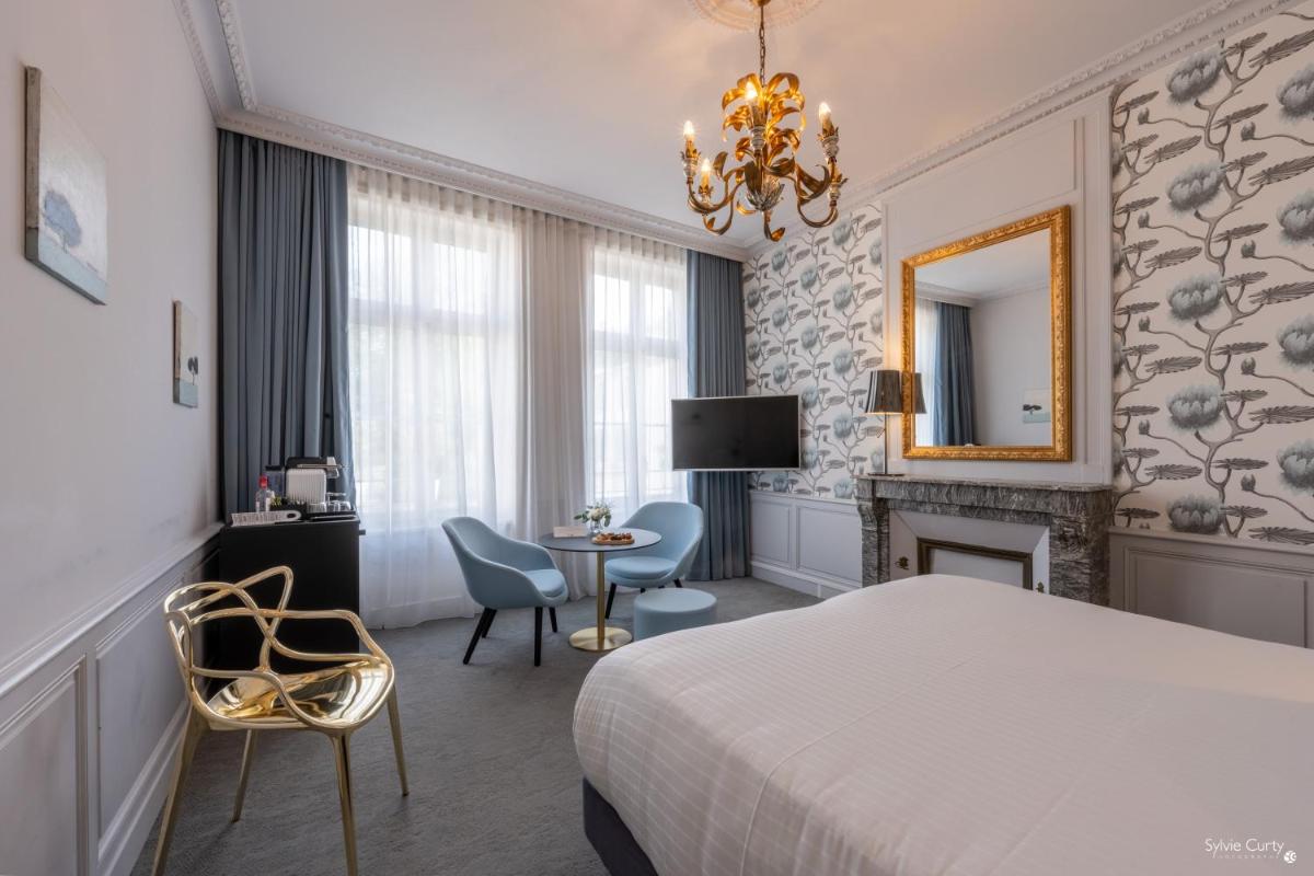 une chambre d'hôtel avec un lit, une table et des chaises dans l'établissement Hôtel La Monnaie Arty & Spa, à La Rochelle
