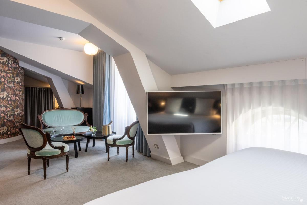 une chambre d'hôtel avec un lit, une table et des chaises dans l'établissement Hôtel La Monnaie Arty & Spa, à La Rochelle