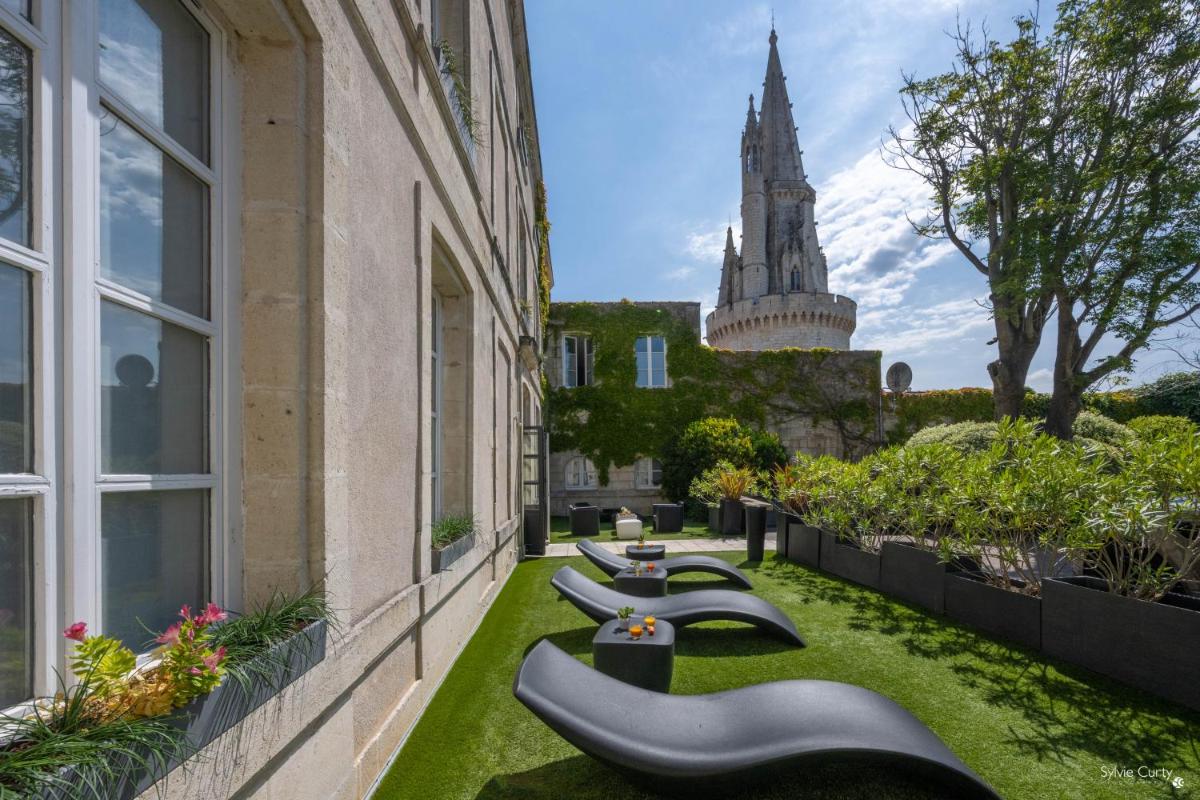 une rangée de bancs sur le côté d'un bâtiment dans l'établissement Hôtel La Monnaie Arty & Spa, à La Rochelle