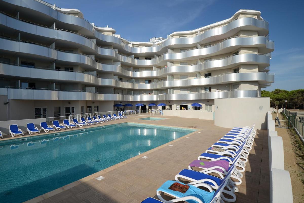 un hôtel avec piscine et chaises longues dans l'établissement Résidence Odalys Le Lotus Blanc, au Barcarès