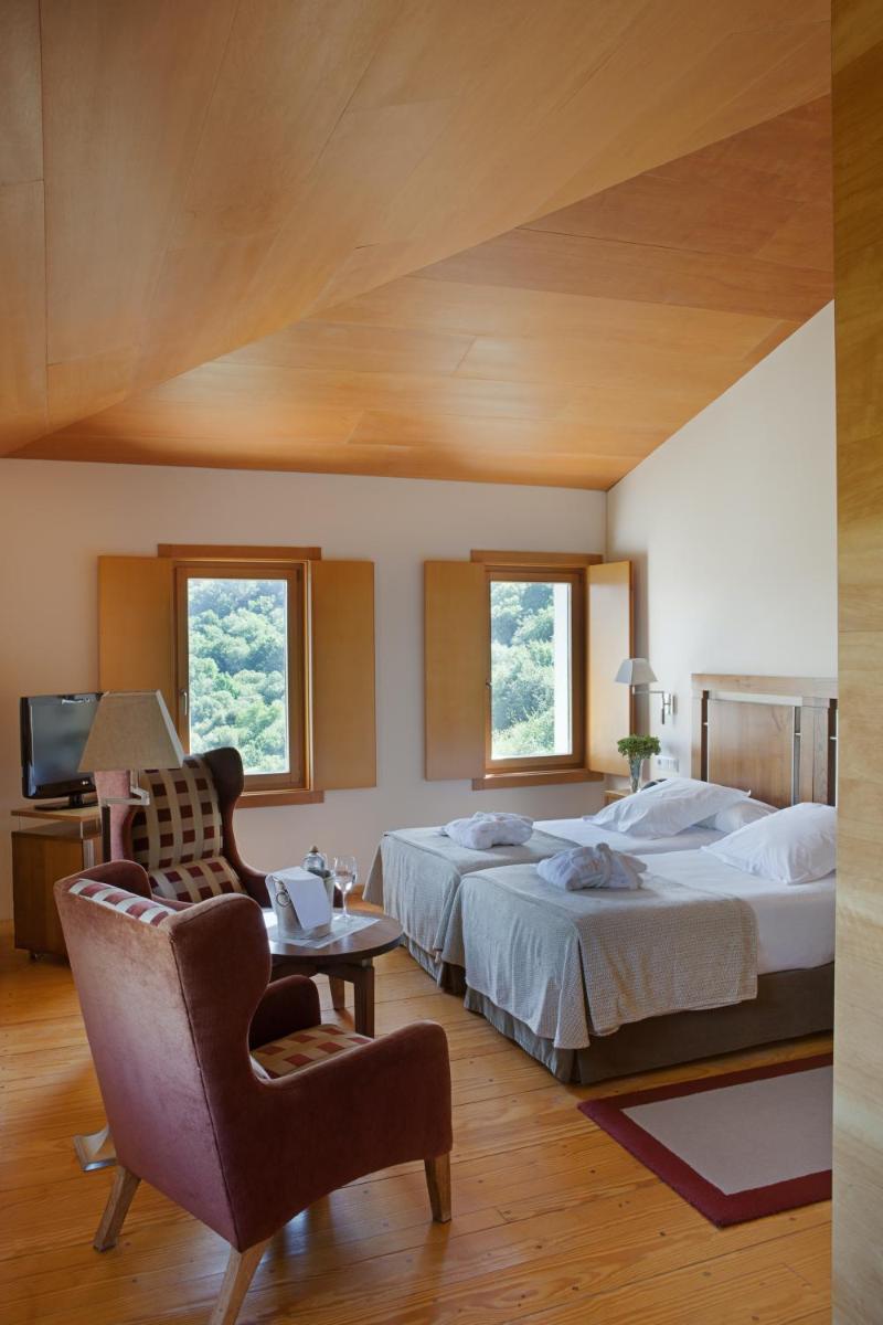 Un dormitorio grande con una cama y una silla. en Parador de Santo Estevo, en Santo Estevo de Rivas de Sil