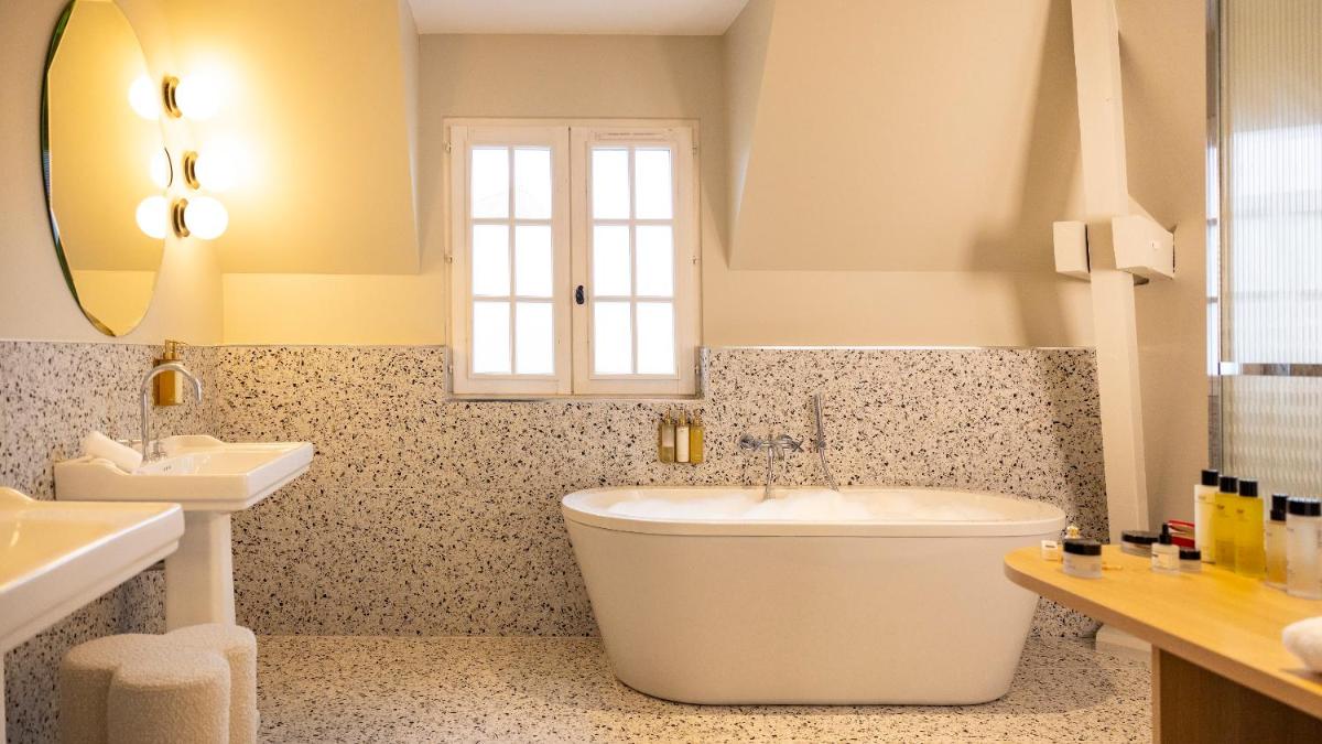 une salle de bain avec une baignoire et un lavabo dans l'établissement Briqueterie Champagne, A Beauvallon Hotel, à Vinay