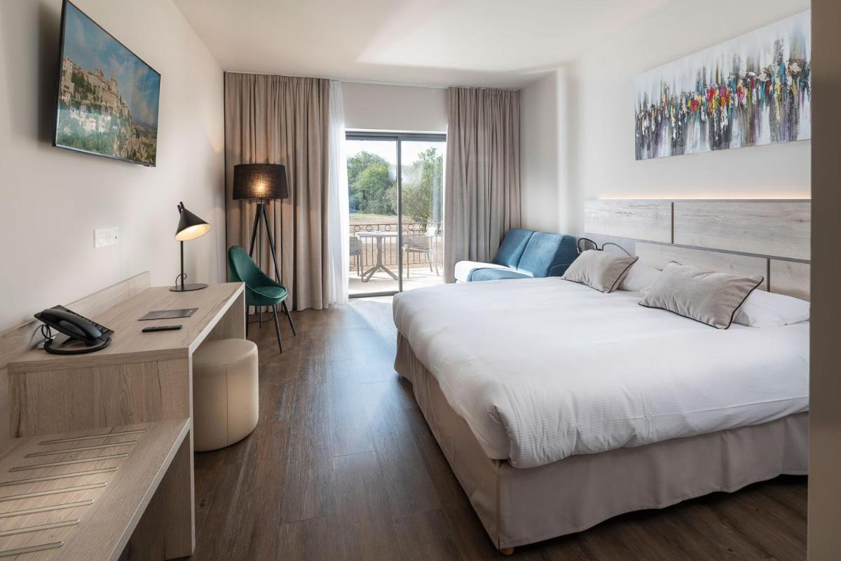 une chambre d'hôtel avec un lit et un bureau dans l'établissement Mas De La Senancole & Spa, à Gordes 58 autres photos