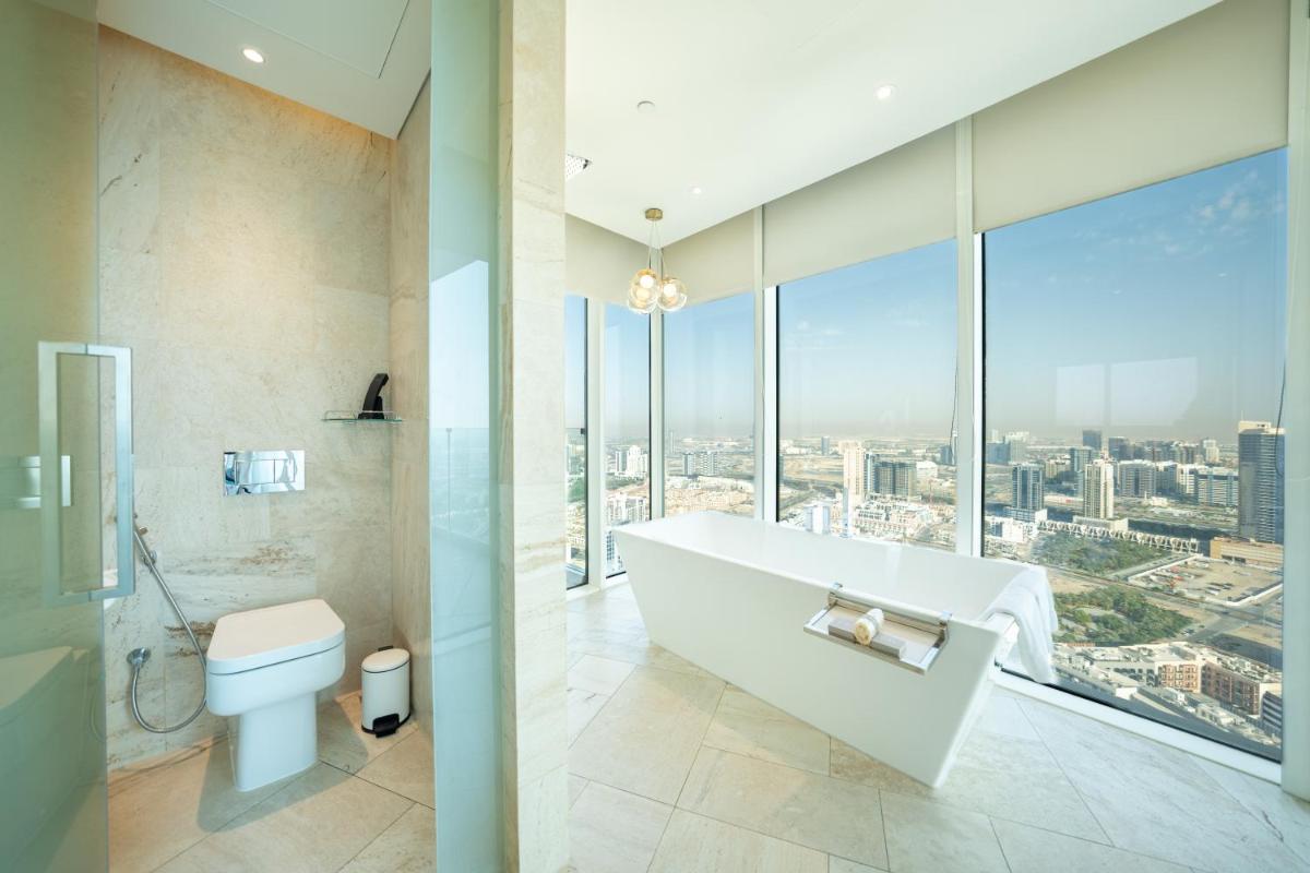 a bathroom with a tub and a toilet and windows at FIVE Jumeirah Village in Dubai a bathroom with a tub and a toilet and windows at FIVE Jumeirah Village in Dubai