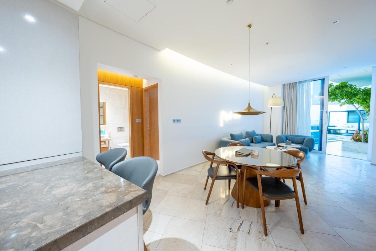 a dining room and living room with a table and chairs at FIVE Jumeirah Village in Dubai a dining room and living room with a table and chairs at FIVE Jumeirah Village in Dubai