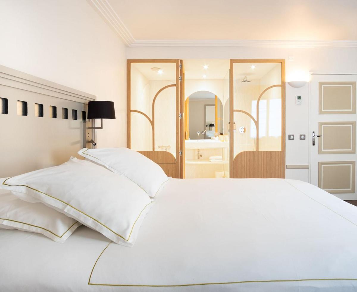 une chambre blanche avec un grand lit blanc et des miroirs dans l'établissement Grand Tonic Hotel & SPA NUXE, à Biarritz
