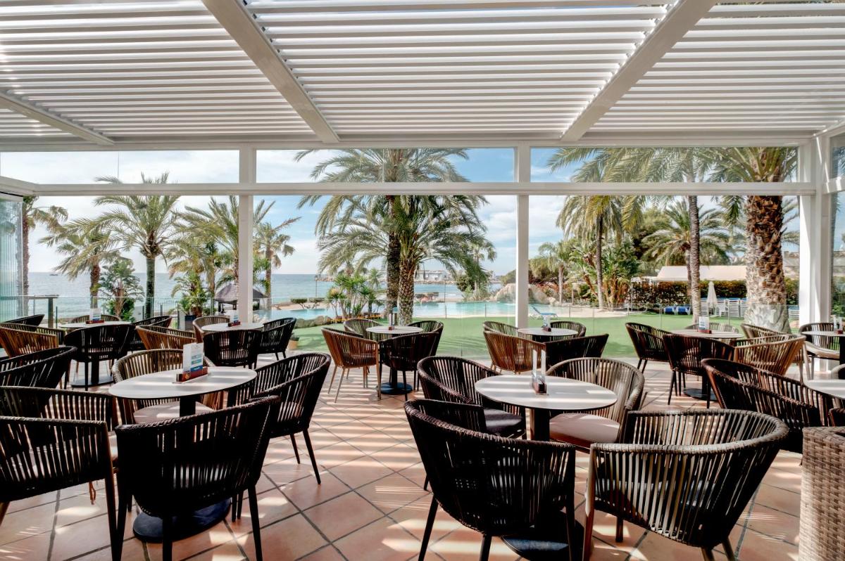 Un restaurante con mesas y sillas y vista al mar. en Gran Hotel Las Fuentes, en Alcossebre