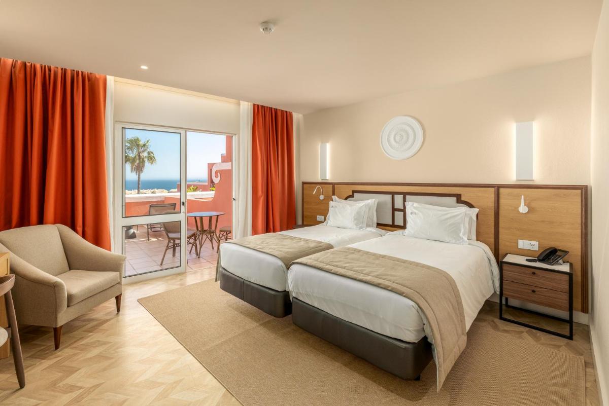 um quarto de hotel com uma cama e uma cadeira em Belavista Da Luz - Wellness & Lifestyle Hotel na Praia da Luz
