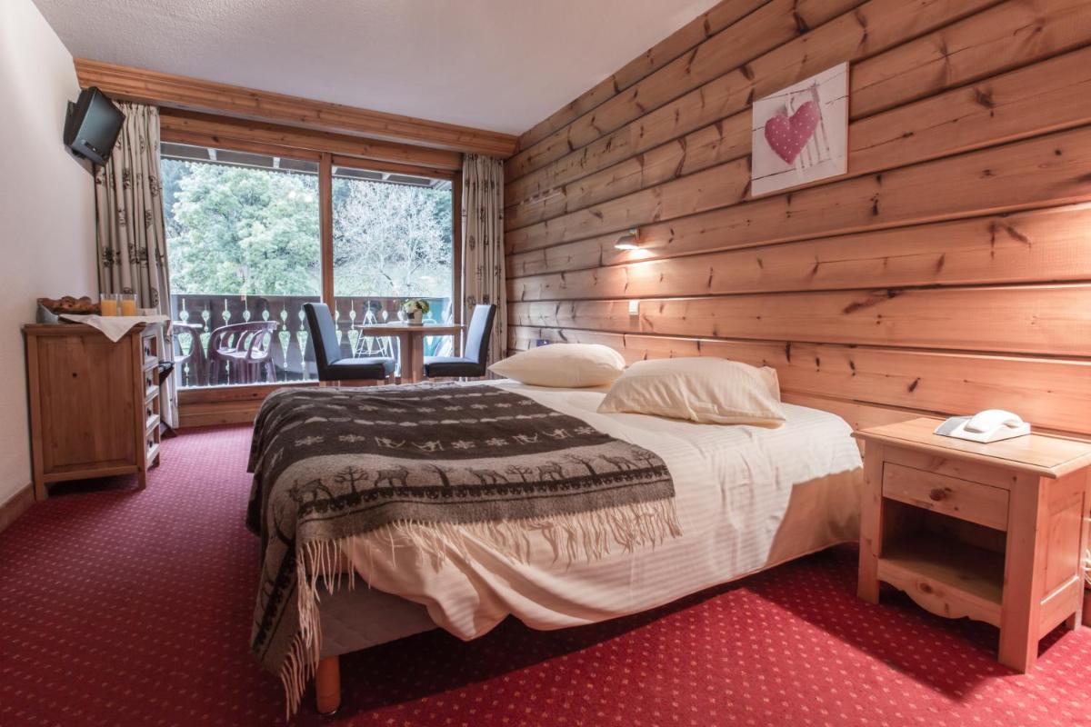 une chambre avec un lit et un mur en bois dans l'établissement Hotel Club Le Crêt, à Morzine