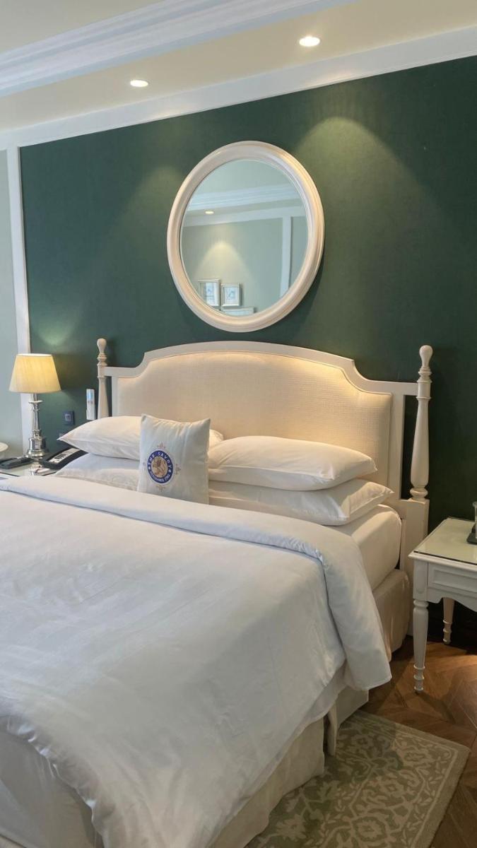 a bedroom with a large white bed with a mirror at Welcomhotel by ITC Hotels, The Savoy, Mussoorie in Mussoorie