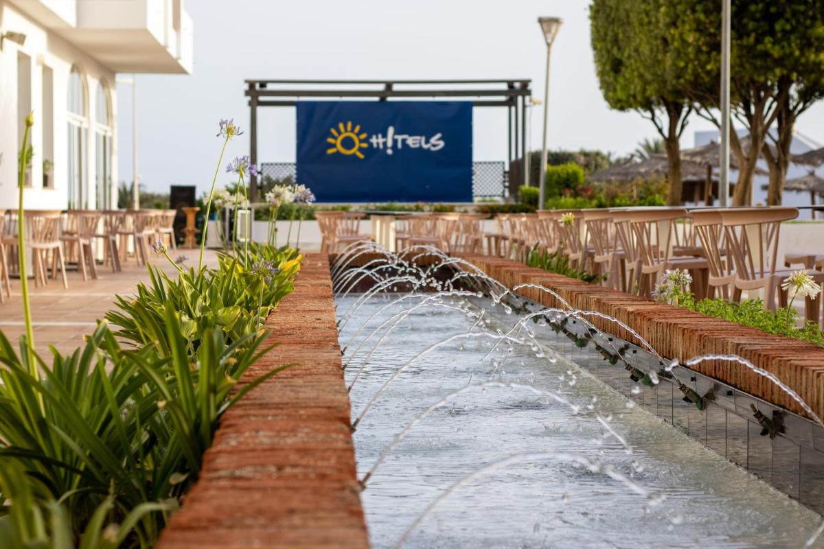 Una fuente de agua con sillas y un cartel al fondo. en Ohtels Cabogata, en Retamar