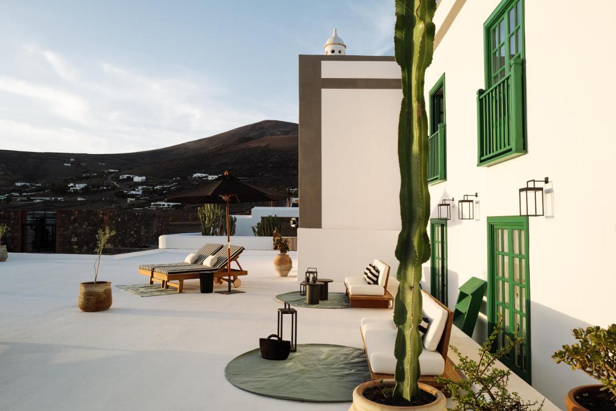 un patio con sillas y una palmera en un edificio en César Lanzarote Luxury Boutique Hotel - Adults Only, en La Asomada