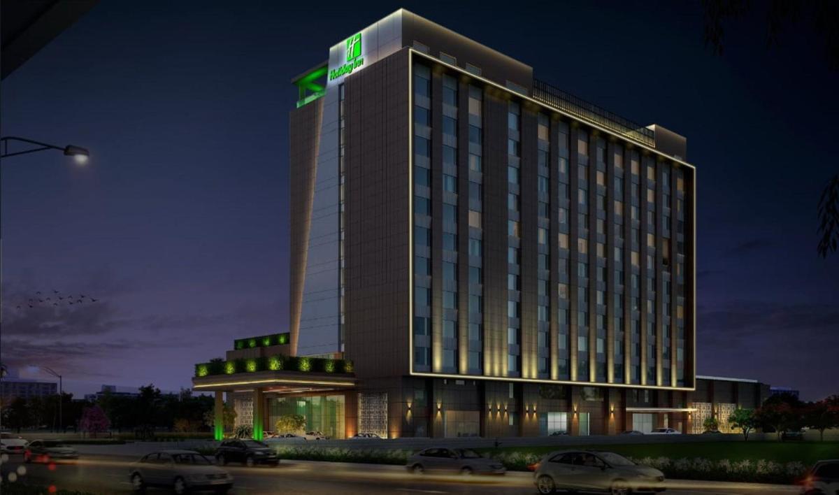 a lit up building with cars parked in front of it at Holiday Inn Lucknow Airport by IHG in Lucknow