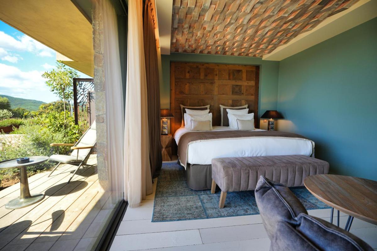 une chambre avec un lit et un balcon avec une table dans l'établissement Les Regalia Hôtel & Spa, à Sainte-Lucie de Porto-Vecchio