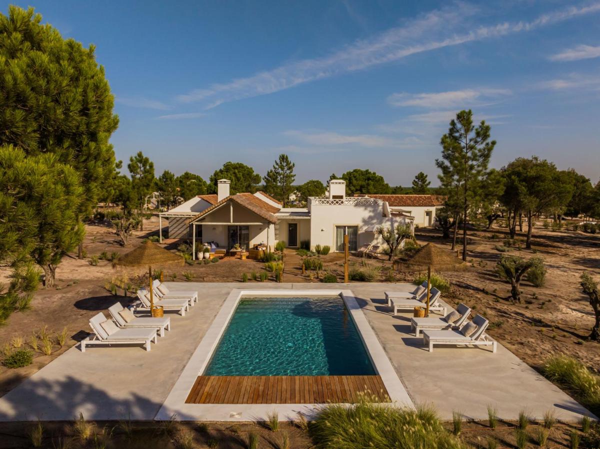 uma vista aérea de uma casa com piscina e cadeiras em Independente Comporta na Comporta