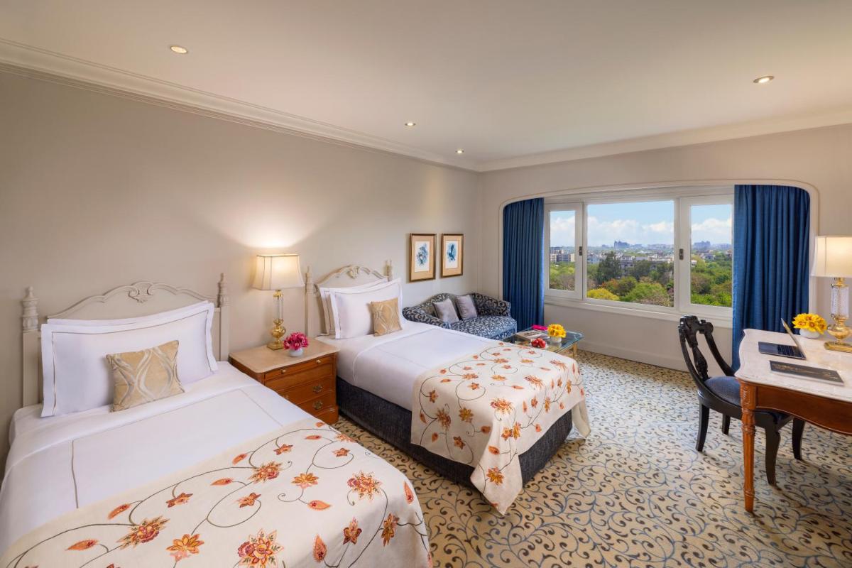 a hotel room with two beds and a desk and a window at Taj Palace, New Delhi in New Delhi a hotel room with two beds and a desk and a window at Taj Palace, New Delhi in New Delhi