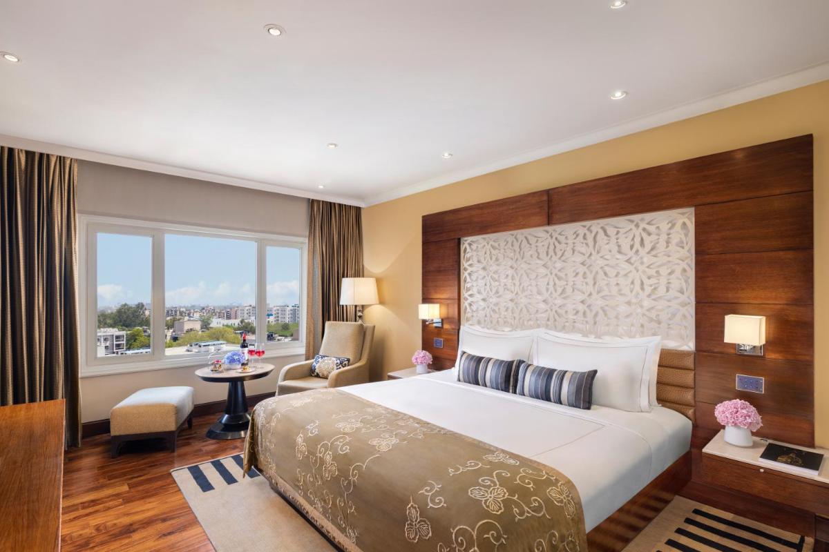 a hotel room with a large bed and a window at Taj Palace, New Delhi in New Delhi a hotel room with a large bed and a window at Taj Palace, New Delhi in New Delhi