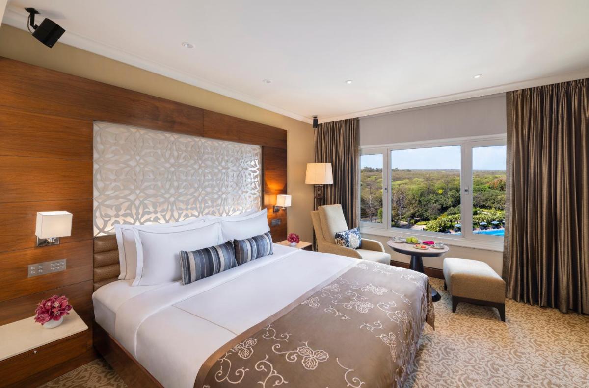 a hotel room with a bed and a large window at Taj Palace, New Delhi in New Delhi a hotel room with a bed and a large window at Taj Palace, New Delhi in New Delhi