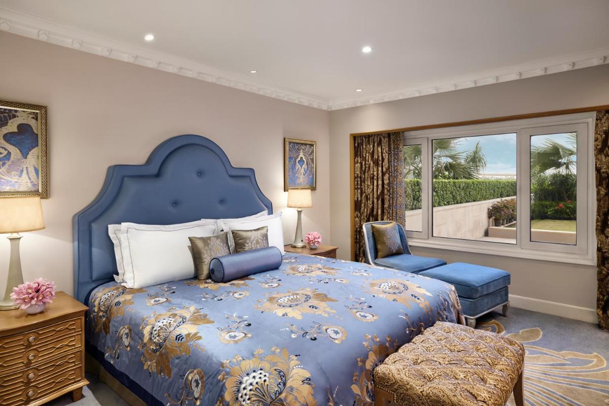 a bedroom with a blue bed and a chair and a window at Taj Palace, New Delhi in New Delhi a bedroom with a blue bed and a chair and a window at Taj Palace, New Delhi in New Delhi