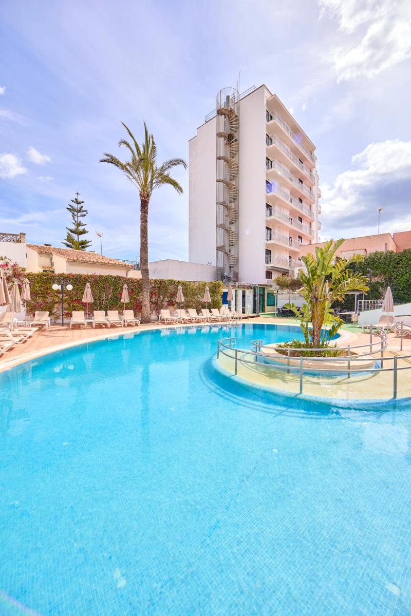Una gran piscina con sillas y un hotel. en Ilusion Markus & Spa, en Can Picafort