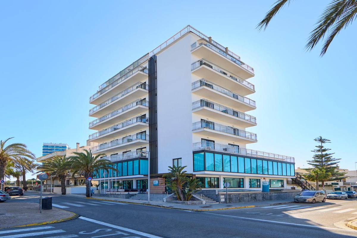 un alto edificio blanco en una calle con palmeras en Ilusion Markus & Spa, en Can Picafort